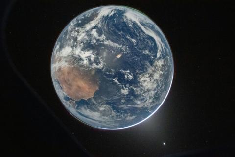 Image fournie par la Nasa montrant la Terre vue à travers le hublot du vaisseau spatial Orion prise par l'astronaute Reid Wiseman, commandant d'Artemis 2, le 2 avril 2026, après la manœuvre d'injection translunaire