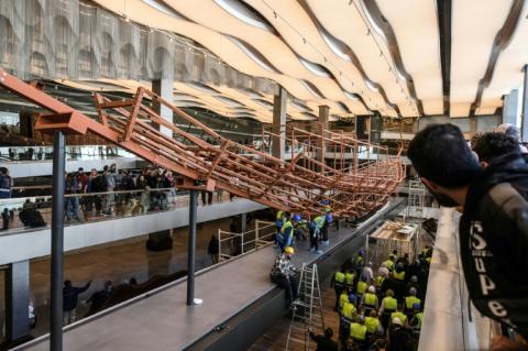 Des employés installent des planches de bois anciennes provenant de la deuxième barque du roi Khéops sur une structure métallique au Grand Musée égyptien de Gizeh, en périphérie du Caire, le 23 décembre 2025