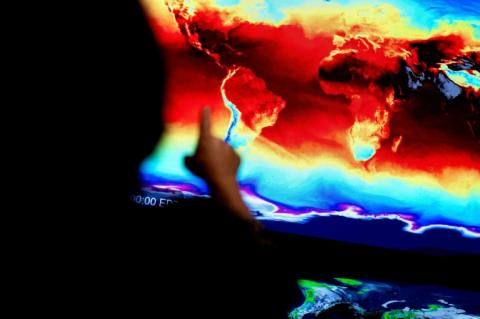 Un employé de la NASA devant une carte du monde affichant les informations transmises par satellites, lors d'une exposition immersive au siège de la NASA à Washington, le 21 juin 2023